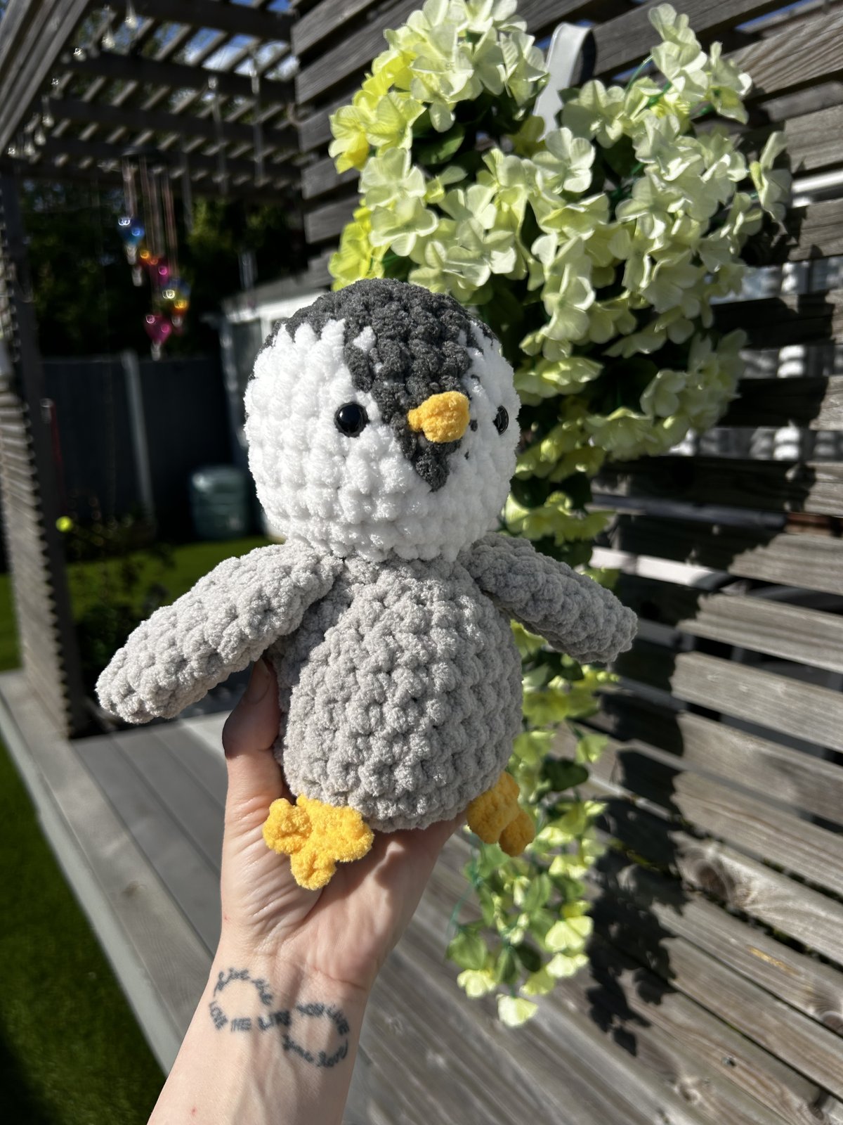 Handmade grey and white crochet penguin plushie with little yellow feet
